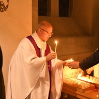 Kaplan Vinzent Piechaczek verteilt das Friedenslicht von Betlehem an die Gottesdienstbesucher.
